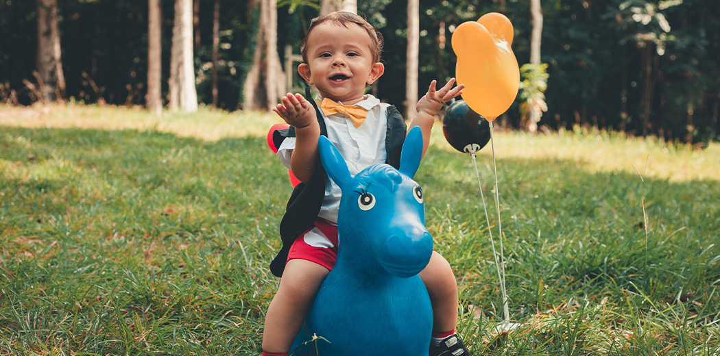 Kid on toy horse raising hands 